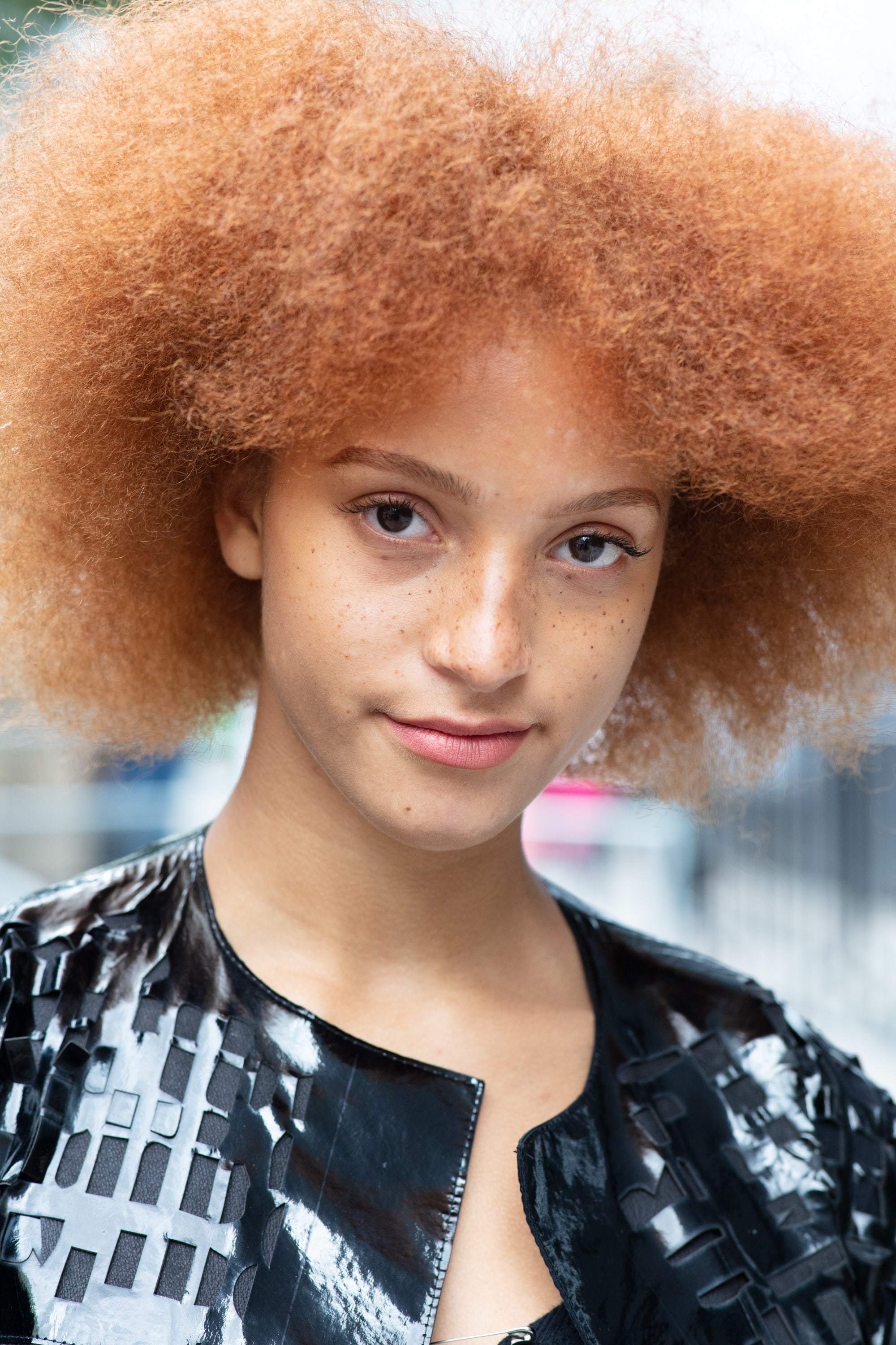 Hair treatment guide: Woman with big, fluffy ginger afro wearing black jacket outside on the street