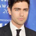 Hairstyles for men over 40: Headshot of Adrian Grenier with dark wavy hair, wearing a suit and tie