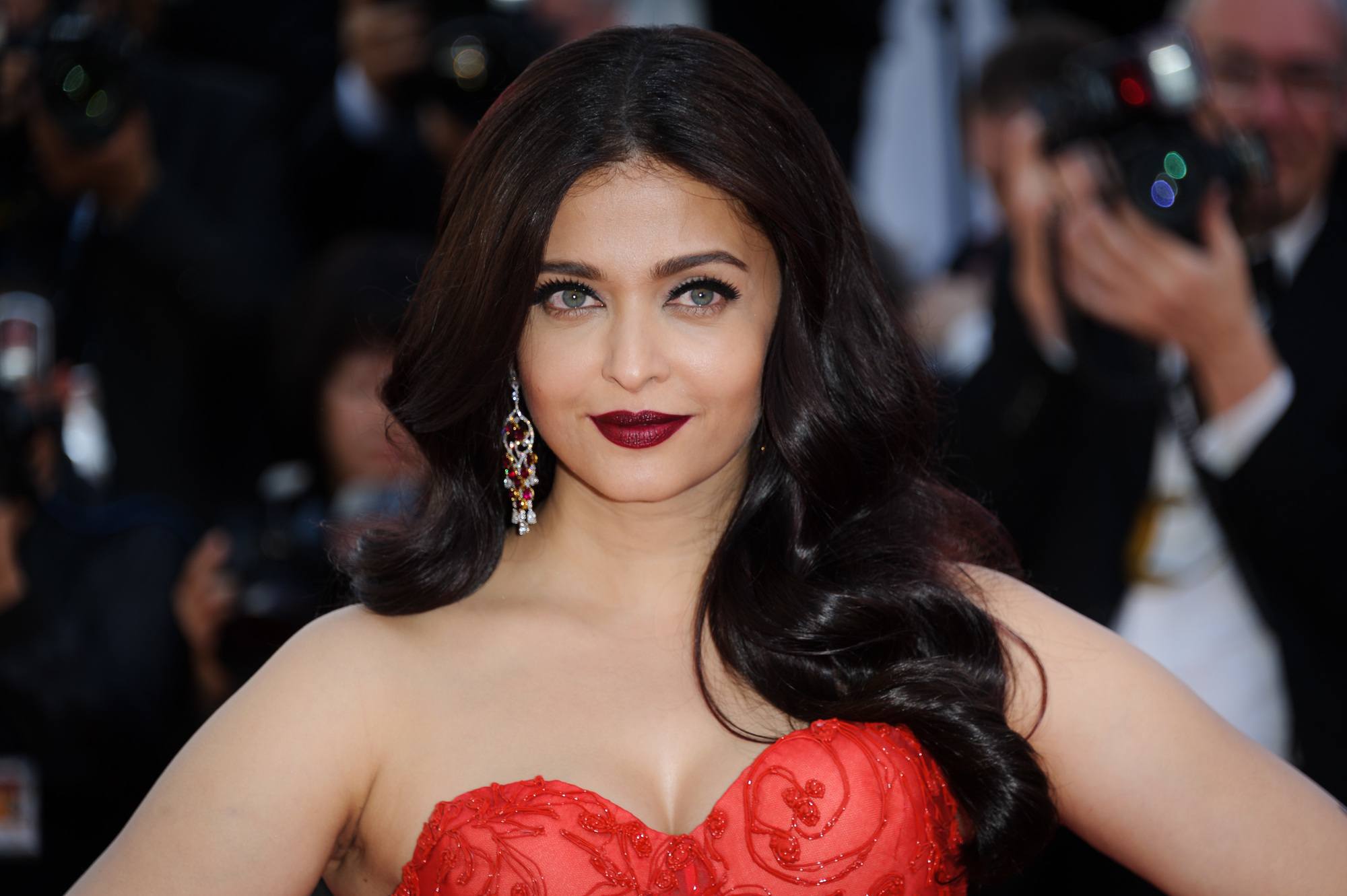 Bollywood hair: Aishwarya Rai with dark brown hair with burgundy tones, styled into Hollywood waves, wearing red dress on the red carpet