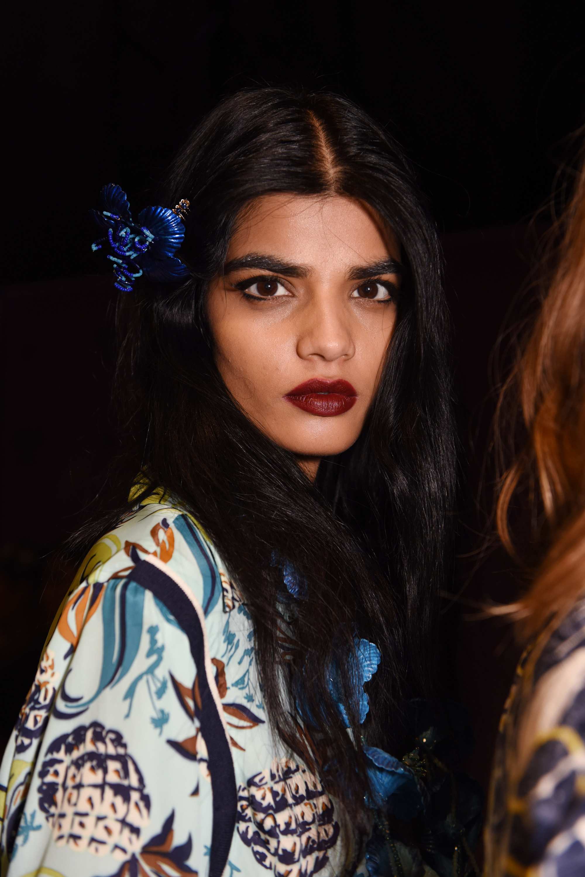 Bollywood hair: Bhumika Arora with dark brown medium hair styled into modern waves wearing a single blue flower in her hair