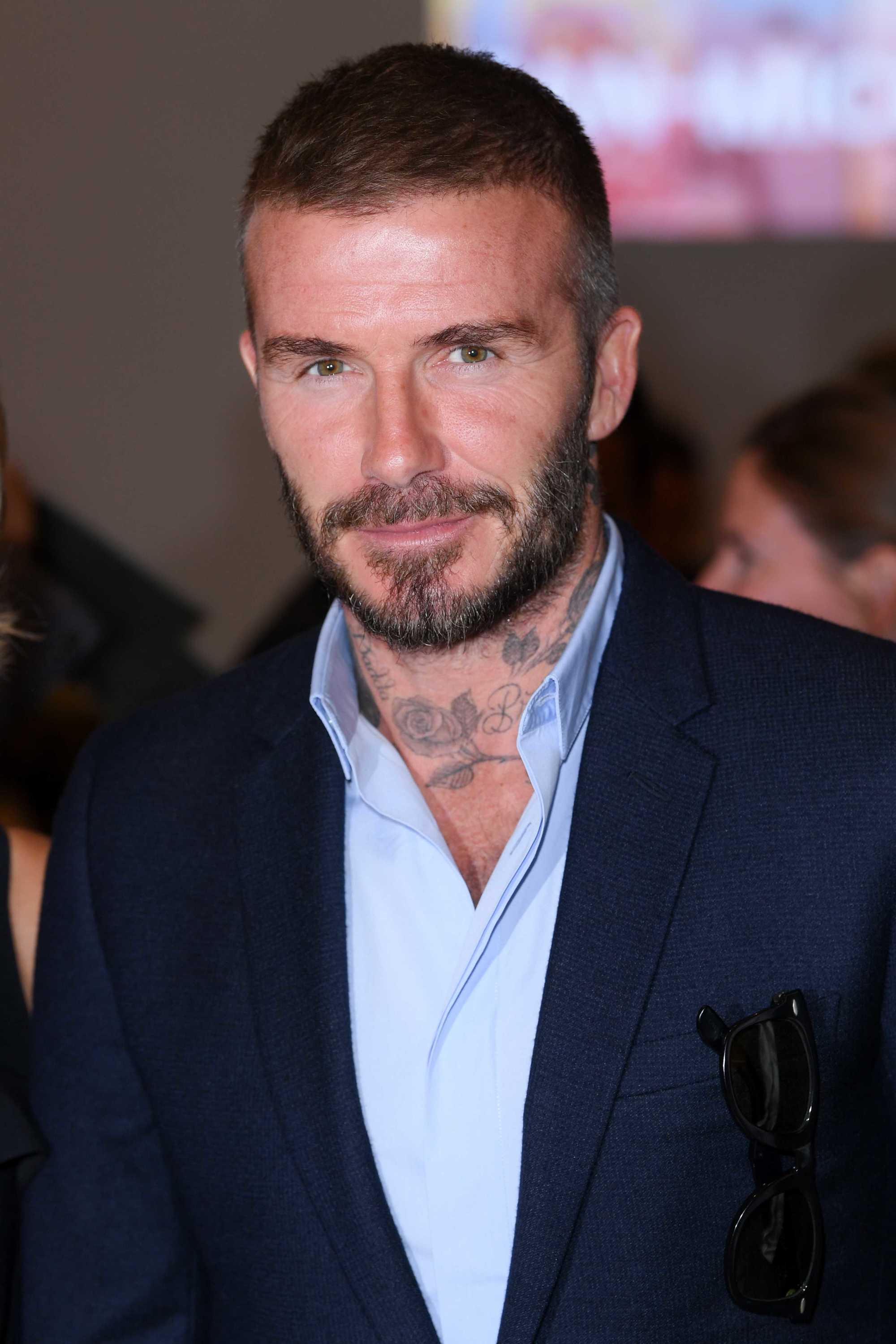 Hairstyles for men over 40: David Beckham with a buzz cut and facial hair, earing a blue shirt and navy suit