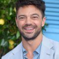 Hairstyles for men over 40: Close-up of Dominic Cooper with brown choppy textured hair, smiling at the camera