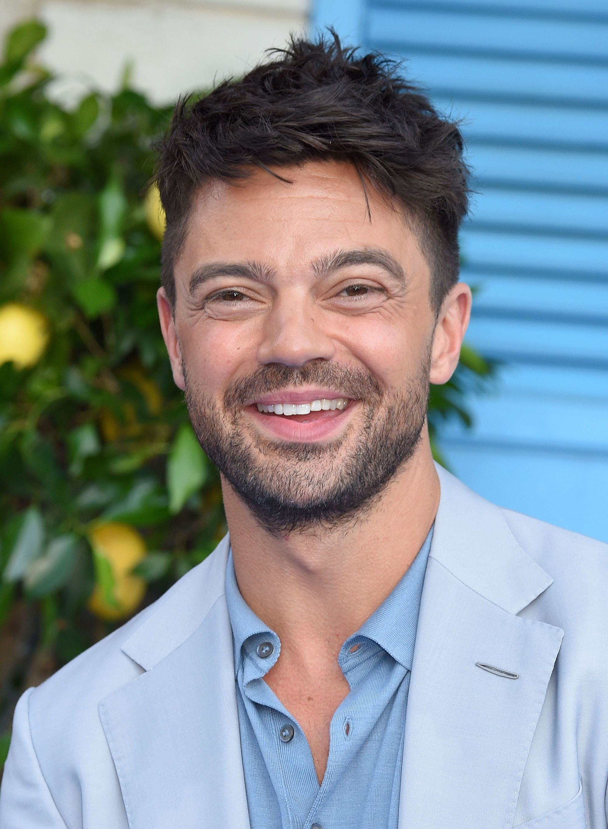 Hairstyles for men over 40: Close-up of Dominic Cooper with brown choppy textured hair, smiling at the camera