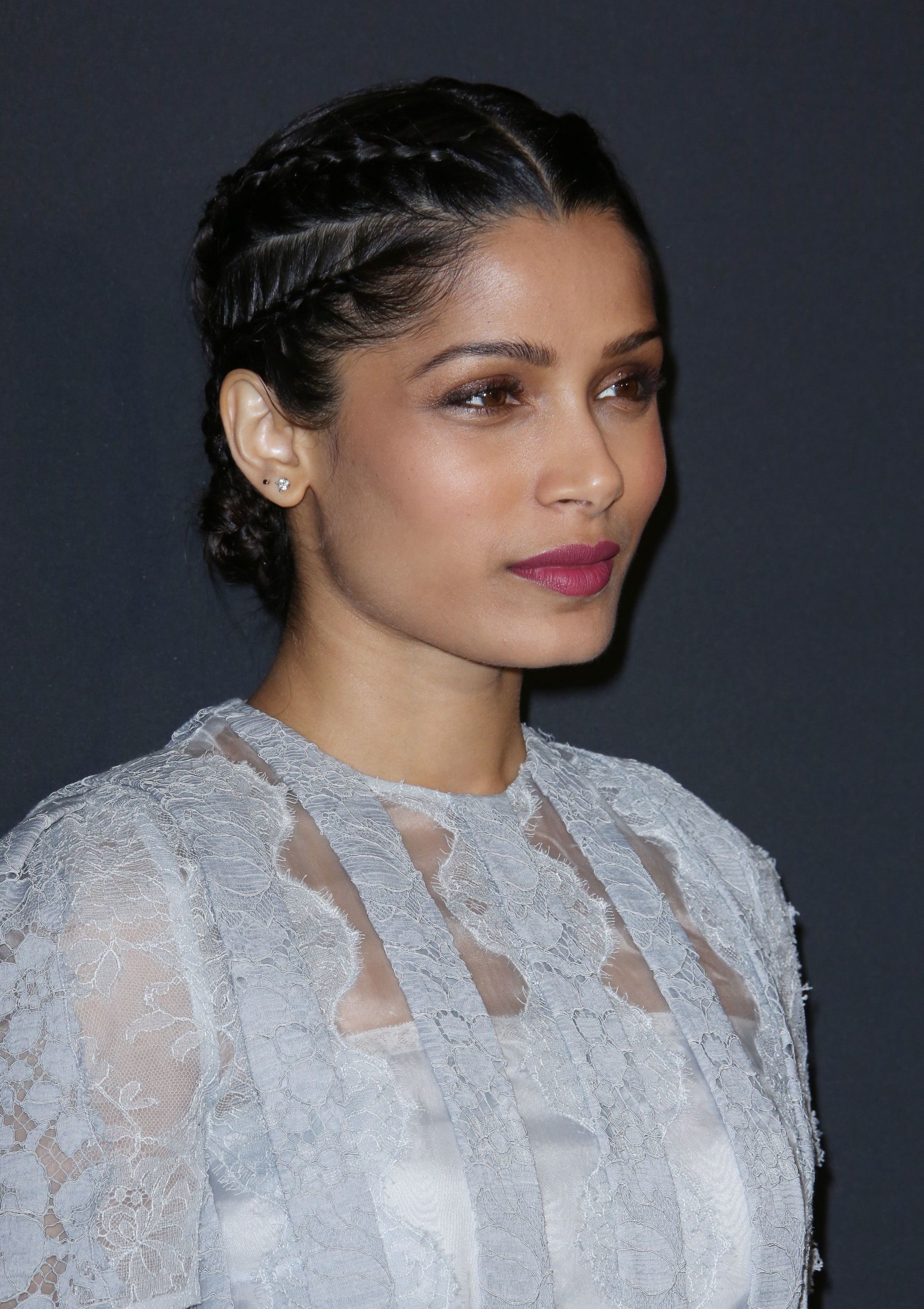 Bollywood hair: Freida Pinto with her medium-length dark brown hair styled into a cornrow braided low bun, wearing light blue lace top on the red carpet