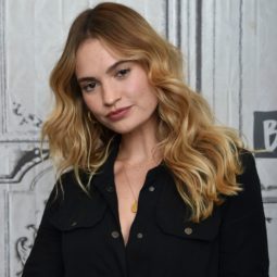 How to use volume spray guide: Lily James with bronde long wavy, voluminous hair, wearing black boiler suit and posing on the red carpet