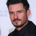 Hairstyles for men over 40: Close-up of Orlando Bloom with curly tousled dark brown short hair