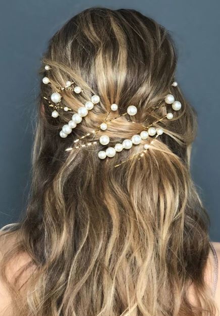Party hair accessories: Woman with highlighted blonde wavy hair styled in a half-up, half-down style adorned with pearl hair accessories.