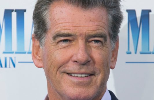 Hairstyles for men over 50: Pierce Brosnan with grey short hair swept back wearing a relaxed blue suit at Mamma Mia premiere.