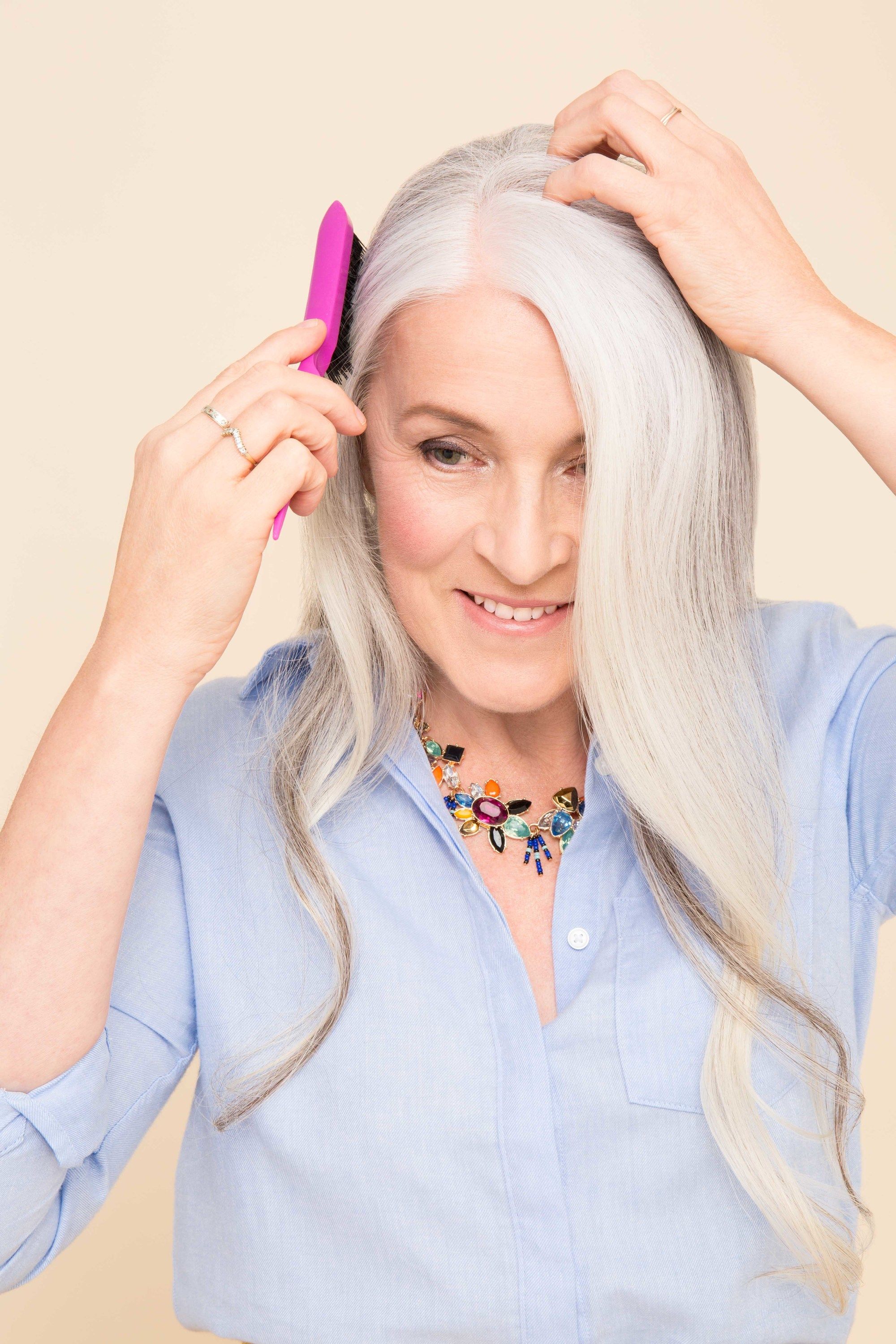 My hair is thinning: Older woman with long grey hair with soft curls, using a pink backcombing brush