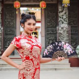 Chinese New Year hairstyles: Asian woman with straight hair in double space buns updo wearing traditional clothing.