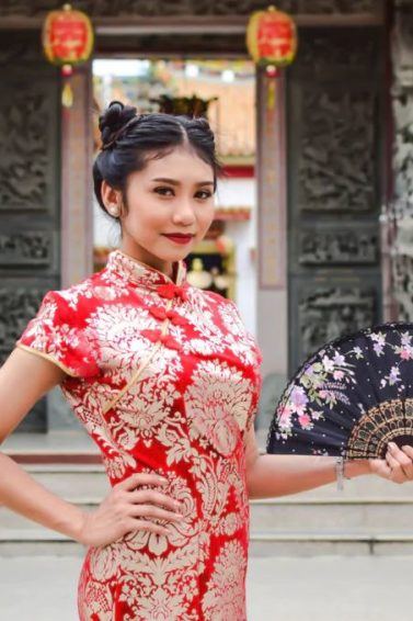 Chinese New Year hairstyles: Asian woman with straight hair in double space buns updo wearing traditional clothing.