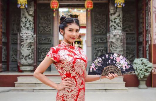 Chinese New Year hairstyles: Asian woman with straight hair in double space buns updo wearing traditional clothing.