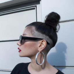 Woman with dark brown long hair styled into a topknot, with an undercut