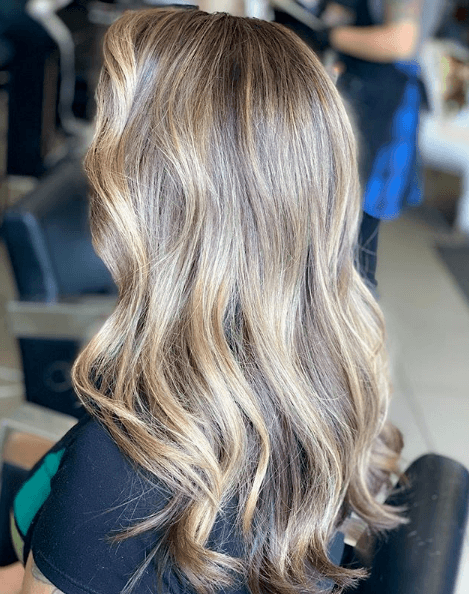 Partial highlights: Back view of a woman with light ash blonde wavy hair with partial highlights