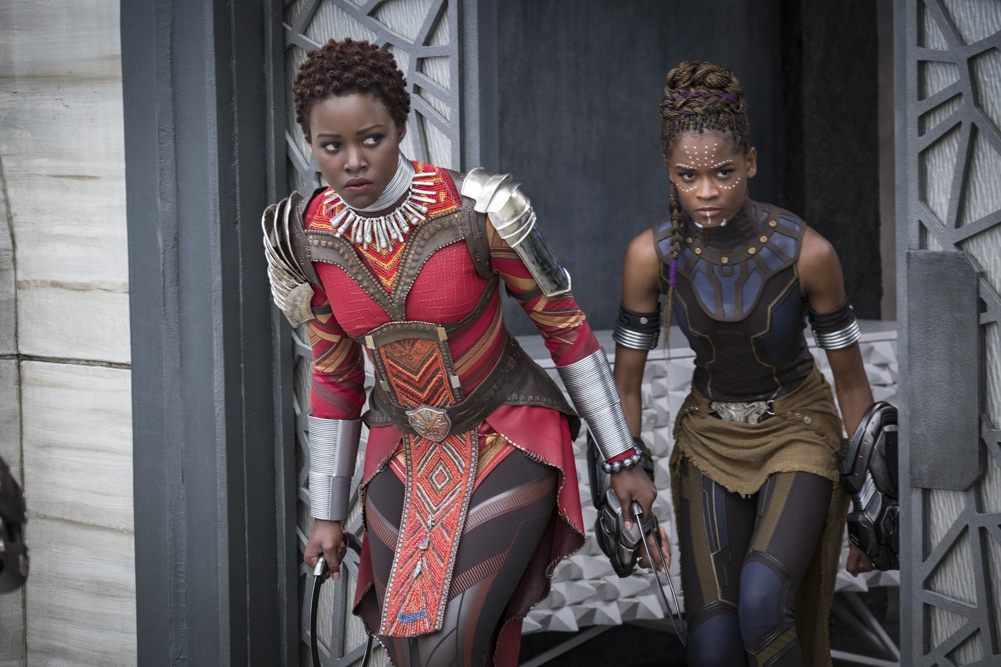 Marvel hairstyles: Lupita Nyong'o playing Nakia in Black Panther with short hair in flat knots bantu knots with Letitia Wright in the background.