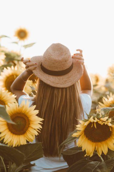 World Earth Day: Woman in a sunflower field with long hair with sunhat on