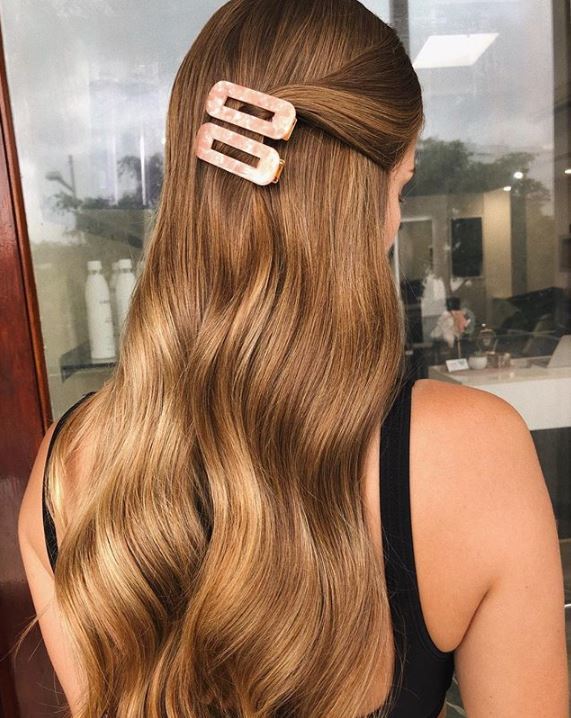 Woman with long wavy blonde hair pinned back.