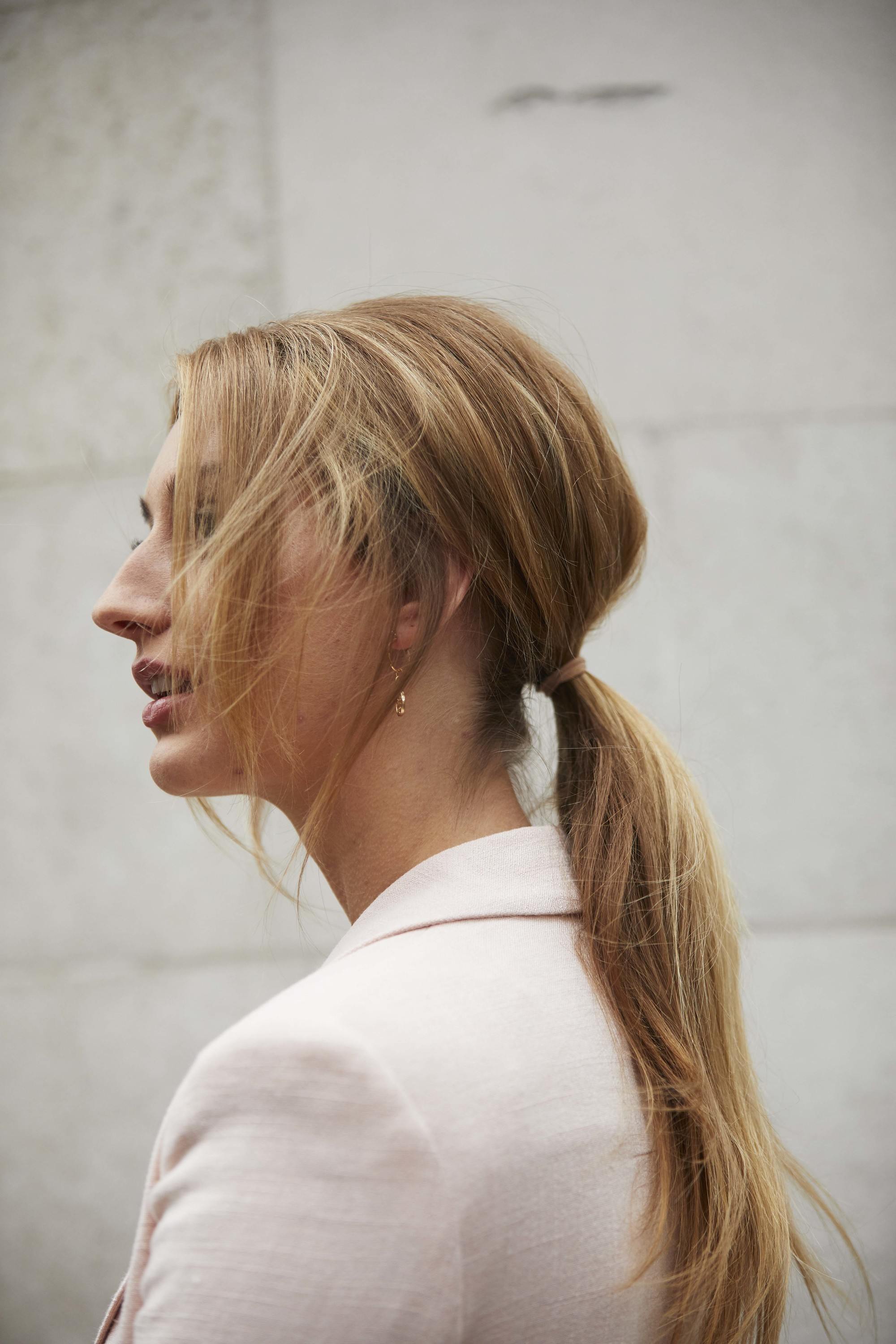 Bridesmaid hairstyles: Woman with golden blonde long hair styled into a ponytail