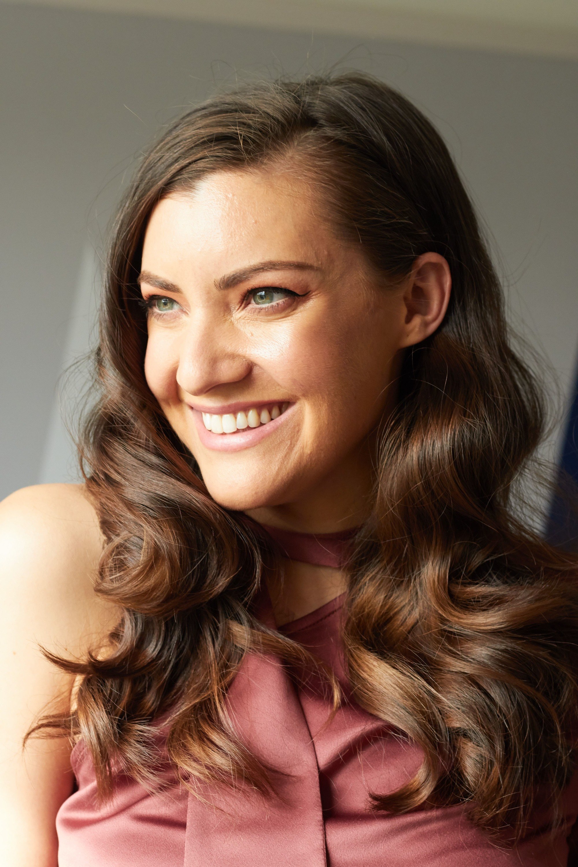 Bridesmaid hairstyles: Woman with dark brown hair styled into retro curls smiling