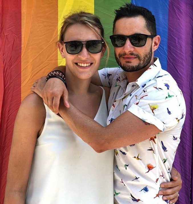 Hannah and Jake Graf hugging in front of a Pride flag