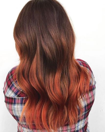 Woman with long wavy black and orange ombre hair