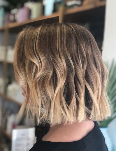 Woman with brown and blonde wavy ombre short hair
