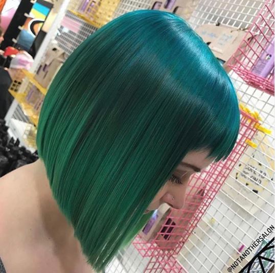 Woman with straight green ombre bob with bangs