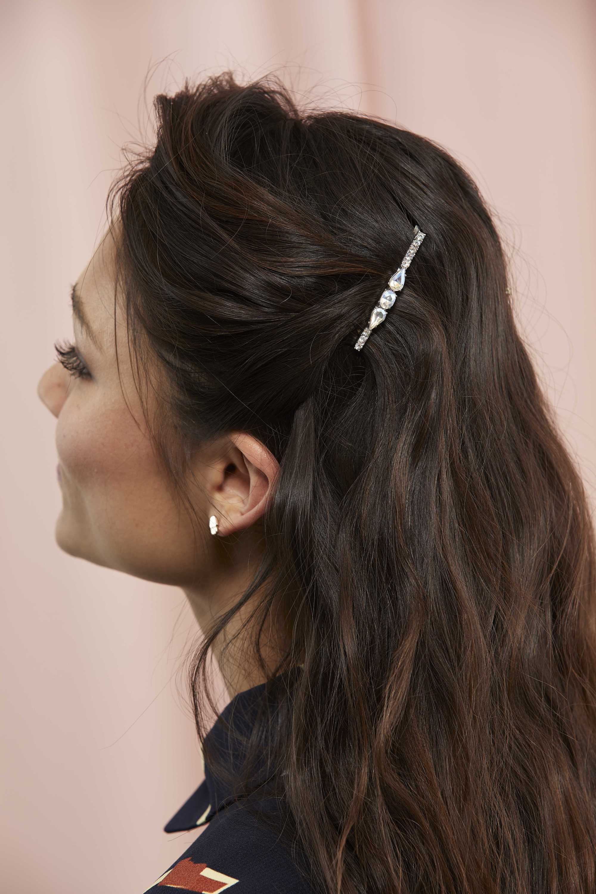 Woman with long dark brown wavy hair with a barrette hair pin