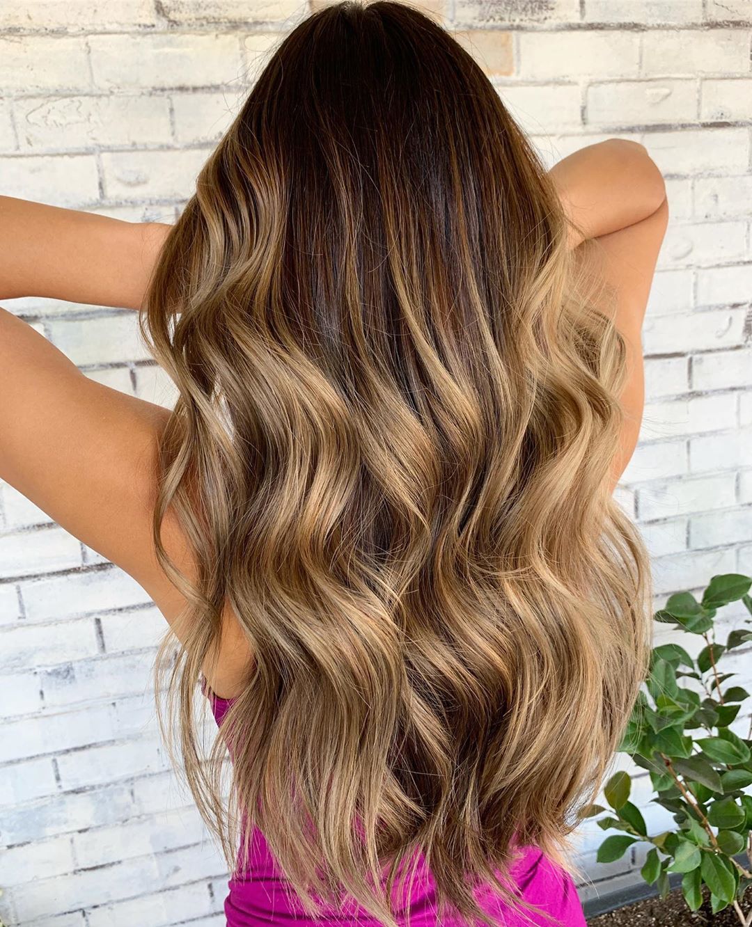 woman with long brown hair with blonde highlights styled into beach waves