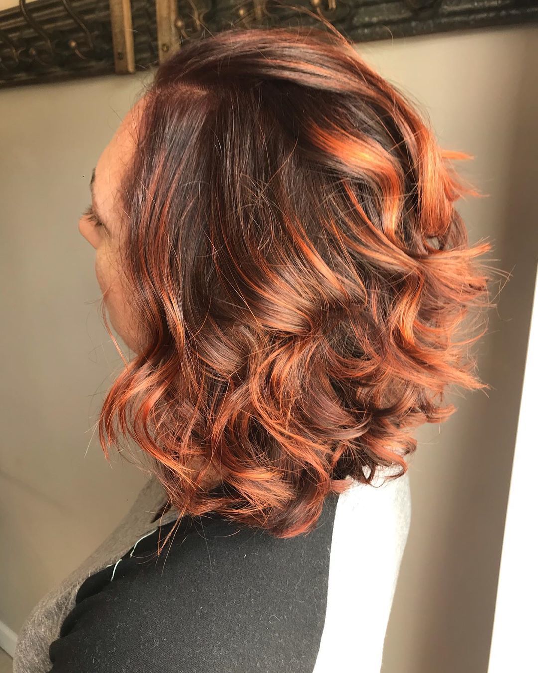woman with long curly bob with copper highlights