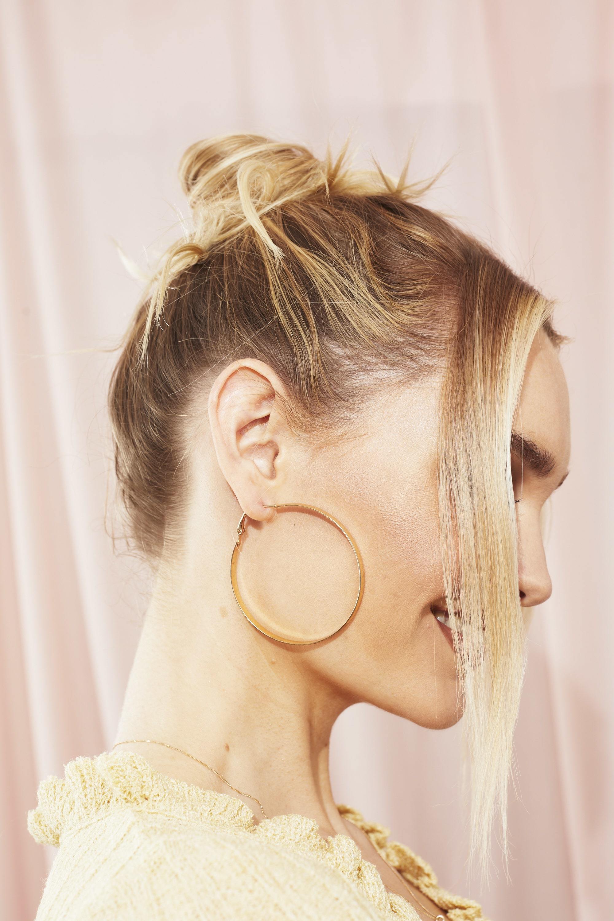 Woman with messy bun hairstyle with tendrils at the front