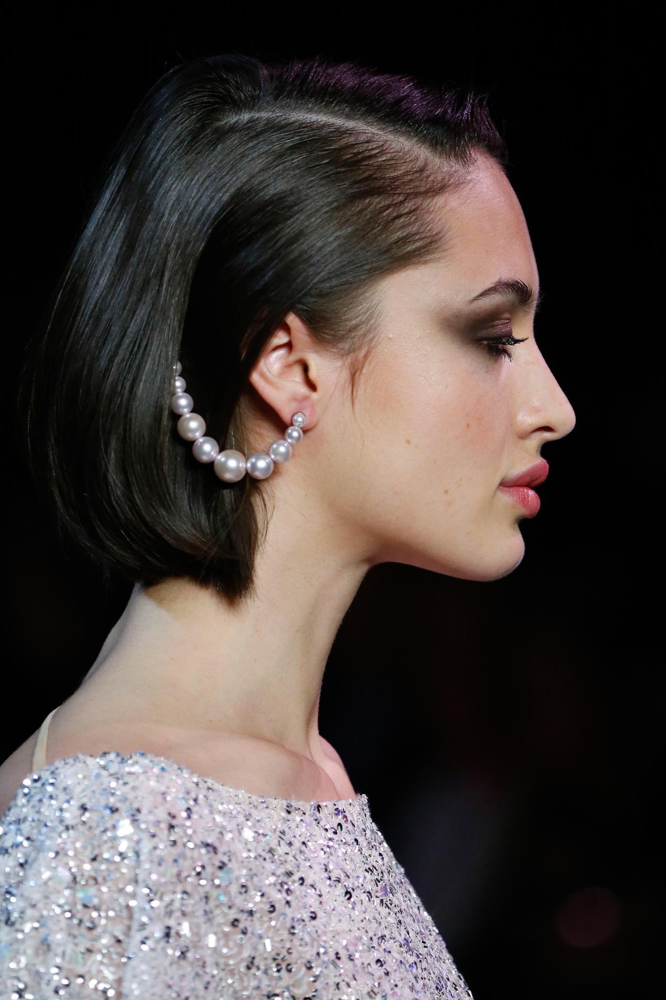 Woman with straight dark brown bob with pearl accessory