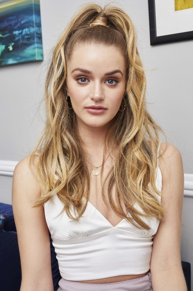 Blonde woman with a wavy half-up half-down ponytail