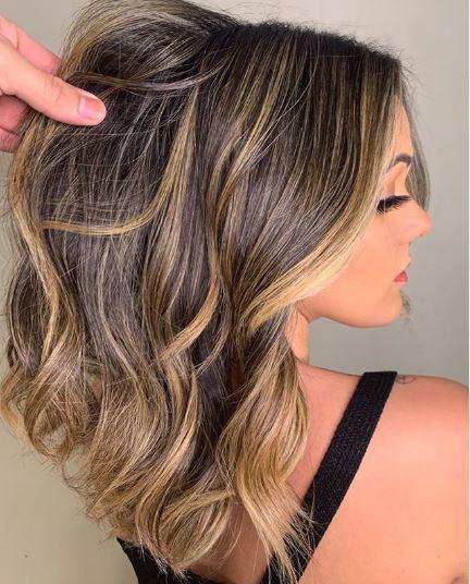 Woman with wavy brown hair and highlights