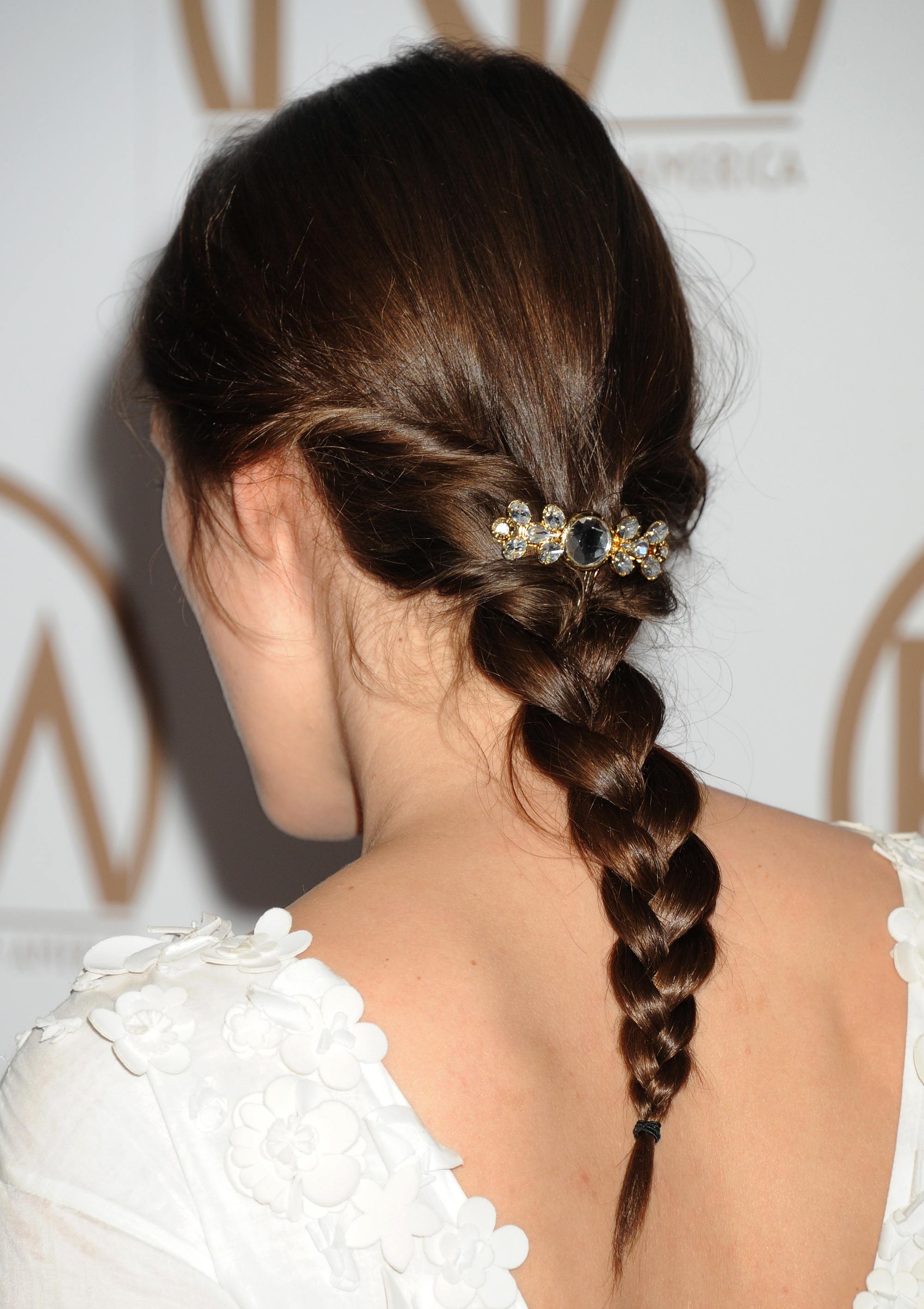 Woman with dark brown hair styled into a low braid with pins