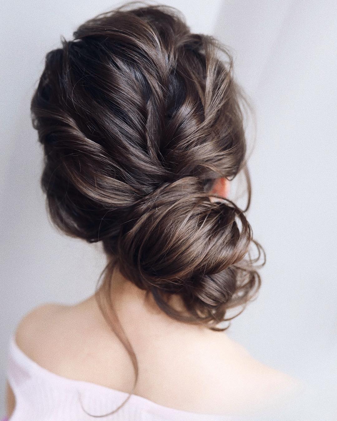 Woman with dark brown hair styled into a messy side bun