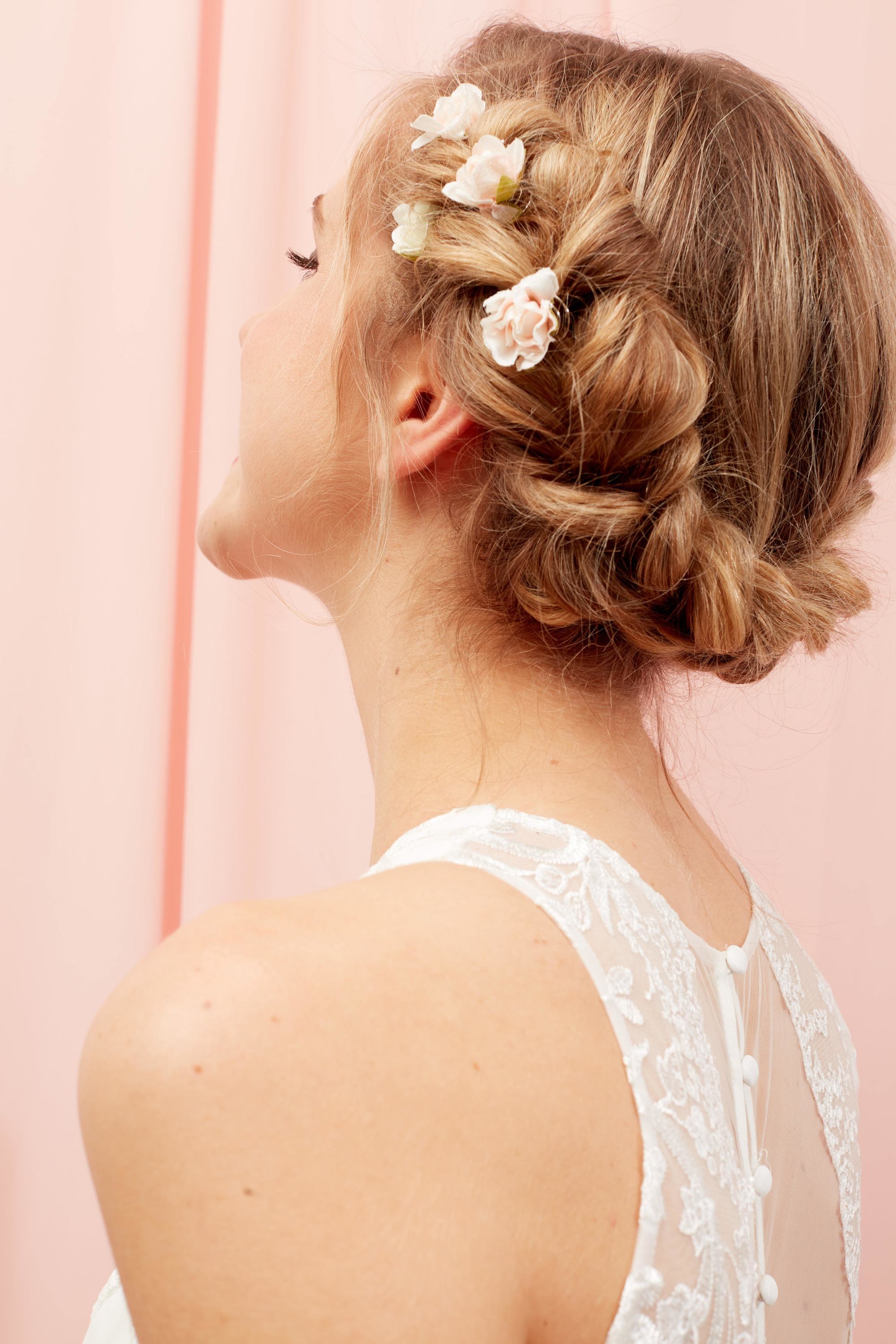 Blonde woman with a crown braid hairstyle with floral hair accessories