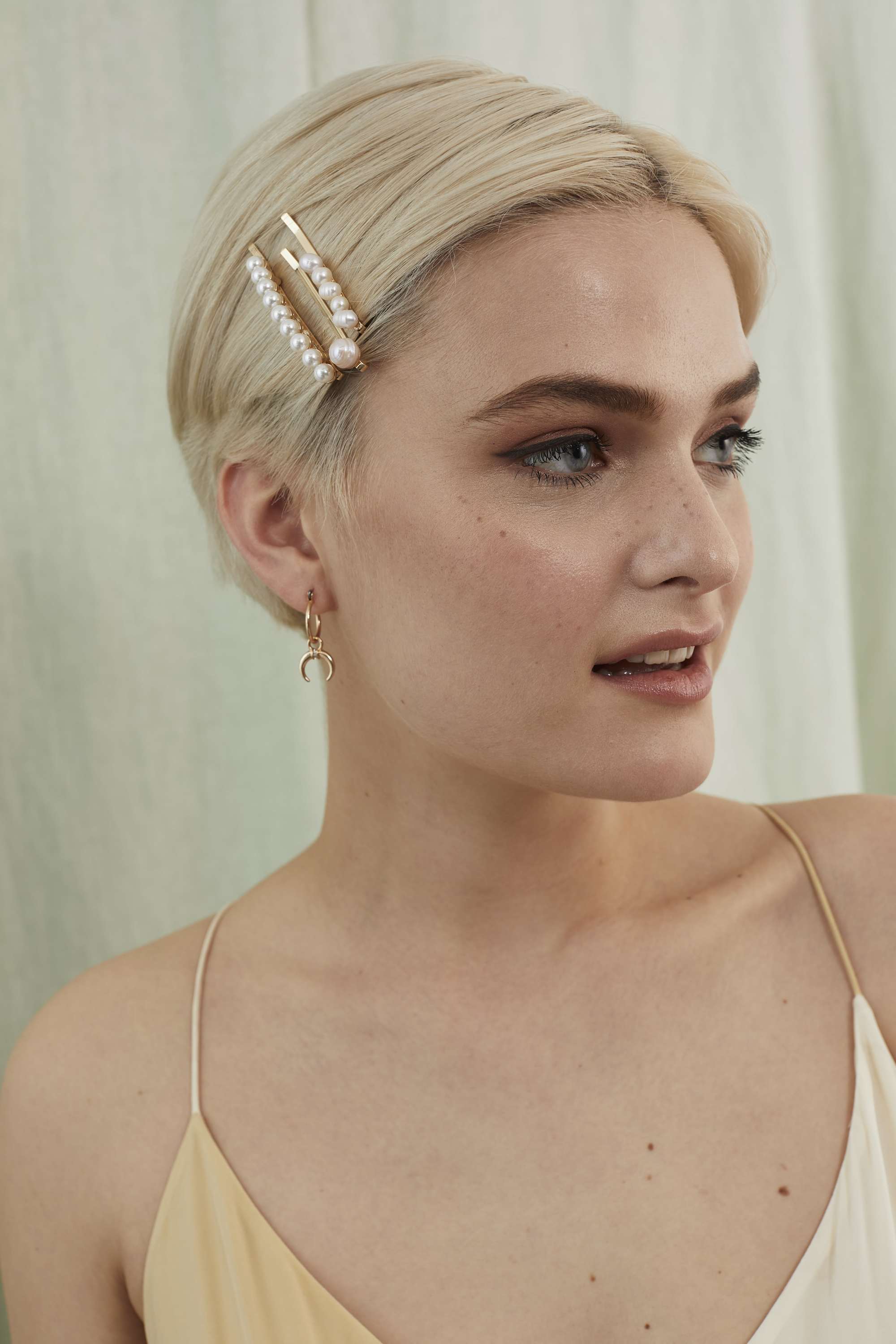 Woman with a sleek blonde pixie cut with pearl hair clips