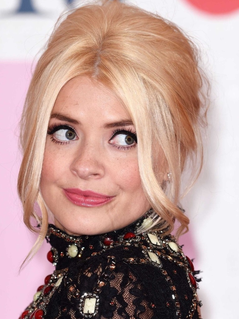 Holly Willoughby hair gallery: Holly Willoughby with blonde hair in a beehive updo with centre parted fringe wearing a black lace and jewelled dress.