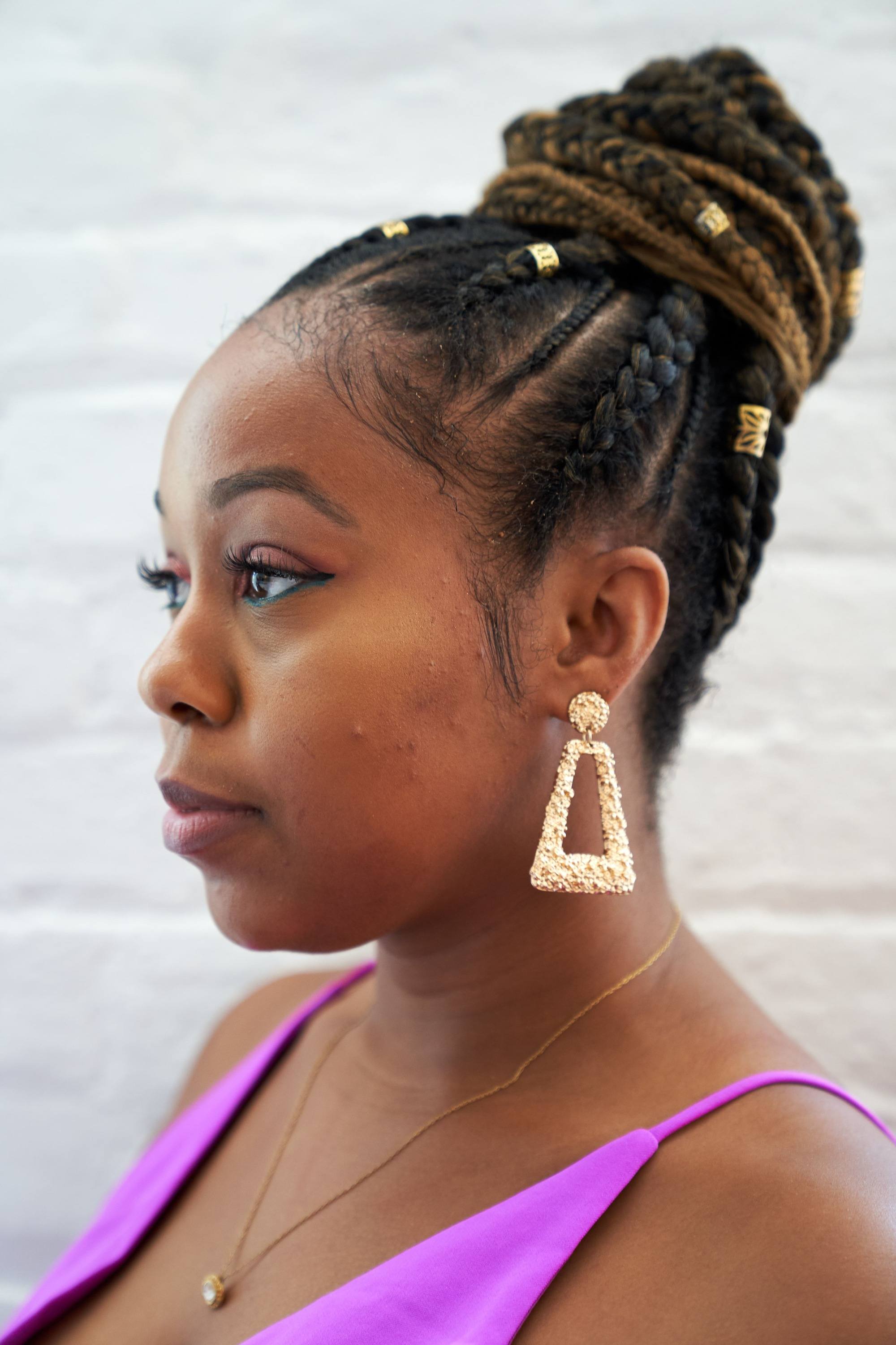 Woman with cornrow braids in a bun with gold cuffs
