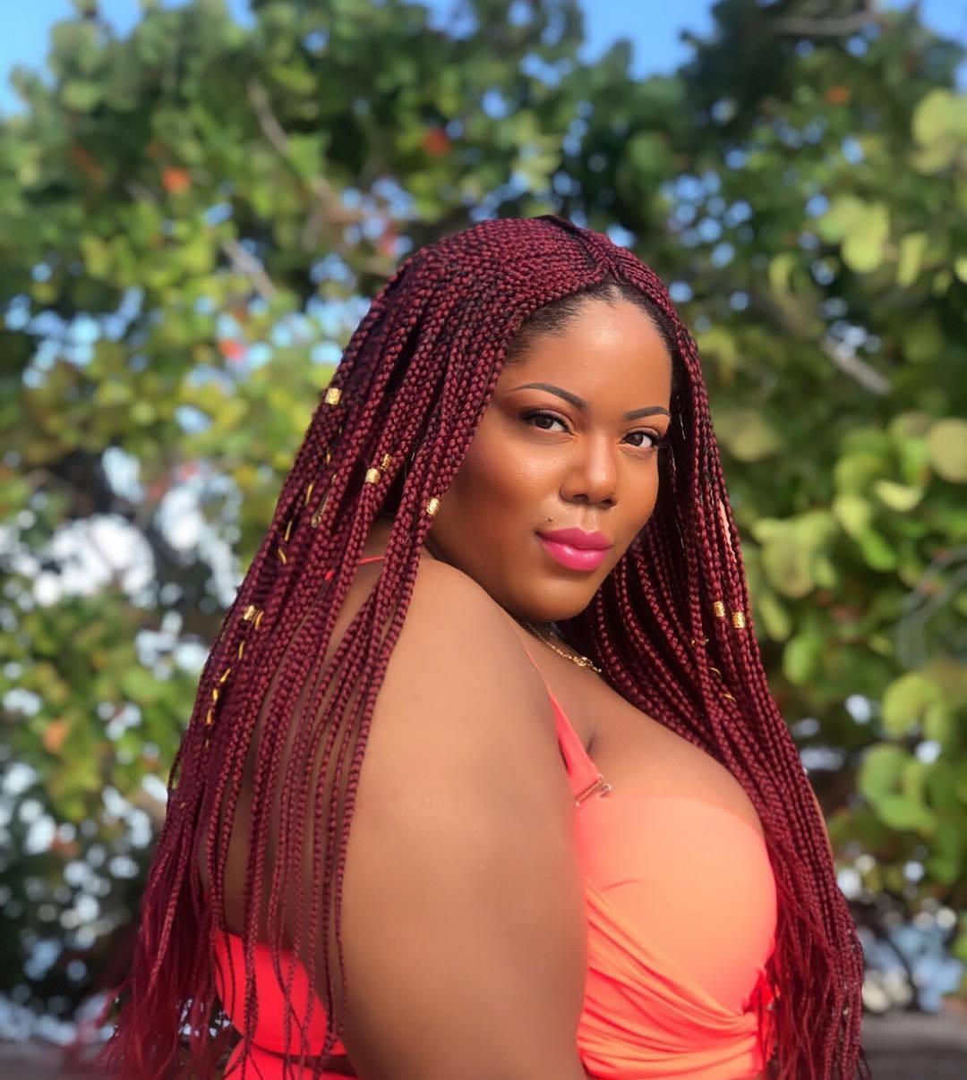 Woman wearing a red cornrow wig with gold cuffs