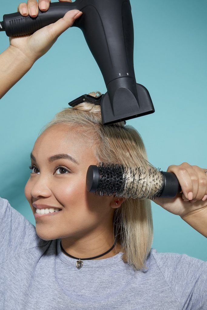 Woman blow-drying bleach blonde hair