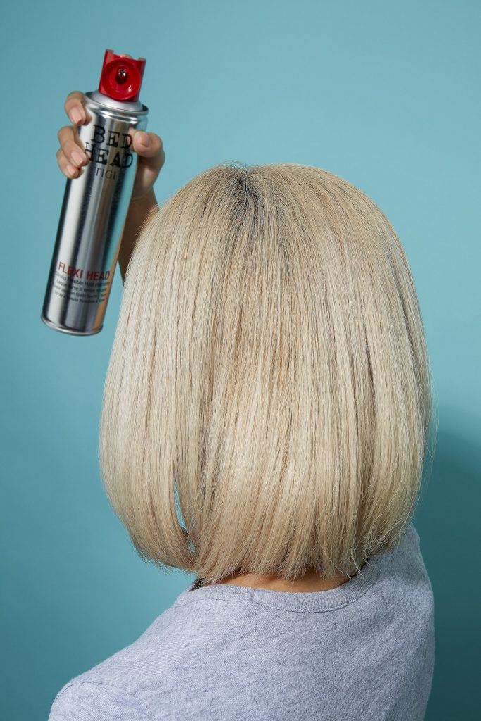 Woman spraying her blonde bob