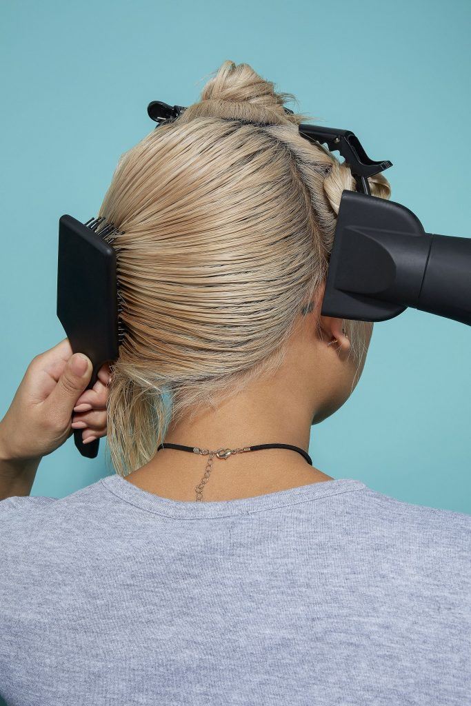 Woman blow-drying bleach blonde hair