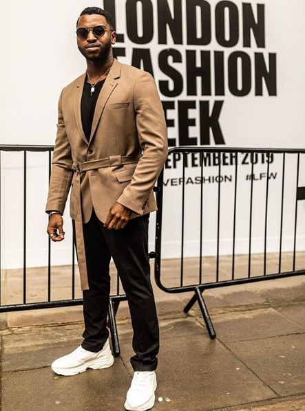 Black bearded man at London fashion week wearing a tan jacket