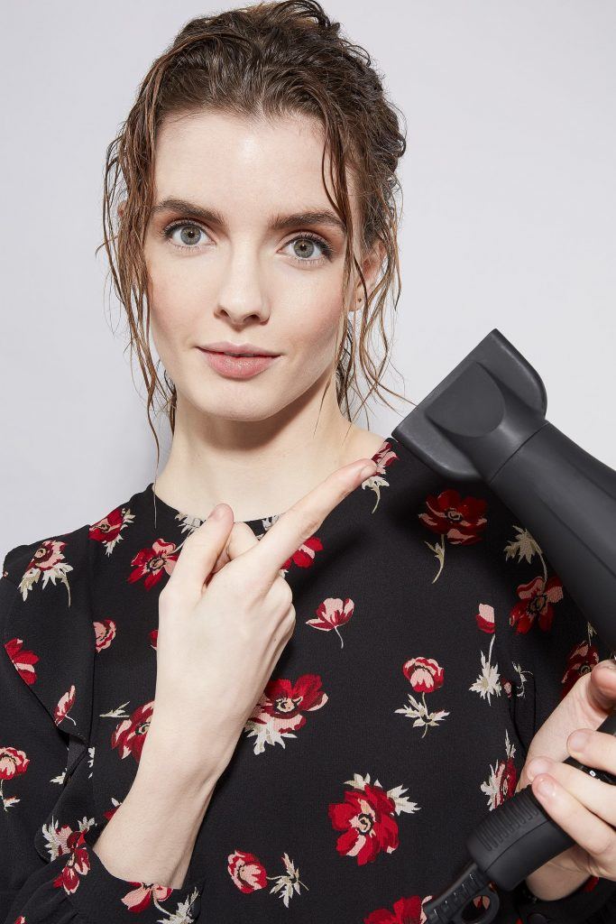 Woman holding a hairdryer with wet hair