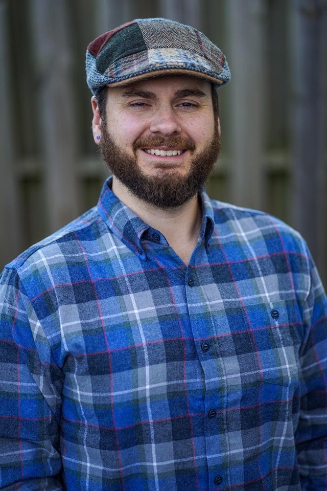 Image of man with plaid top and beard smiling