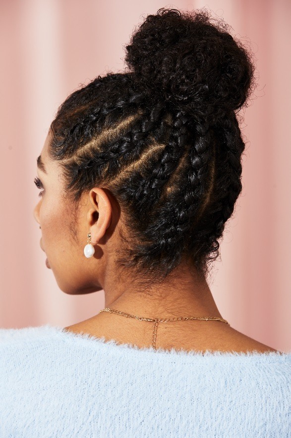 Woman with dark curly hair in a cornrow braided bun