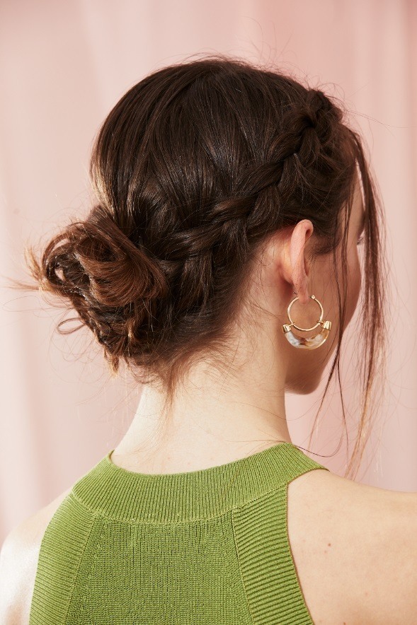 Brunette with a messy braided bun with loose face-framing strands