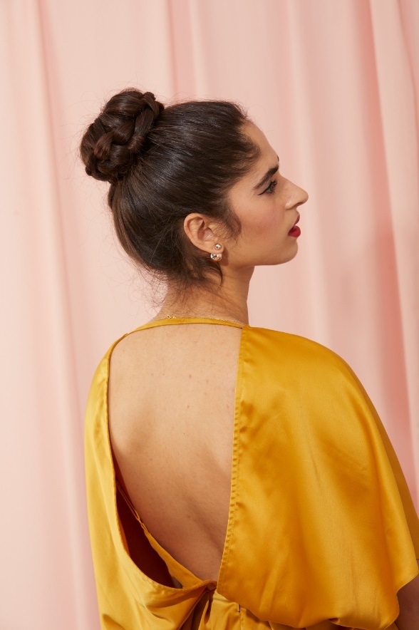 Woman with dark brown hair in a high braided ballerina bun